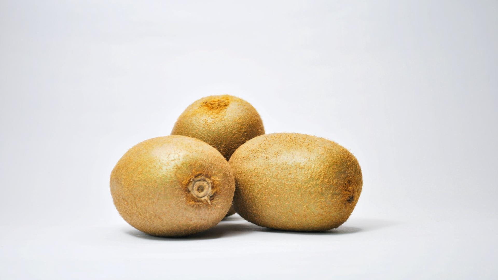 three yellow round fruits on white surface